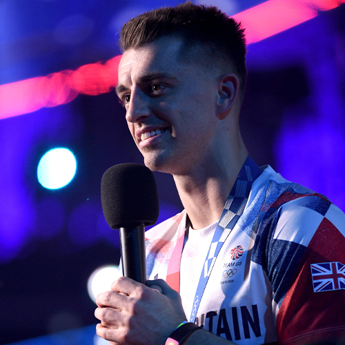 Team Great Britain athlete holds a microphone at the national lottery homecoming event at AO arena.